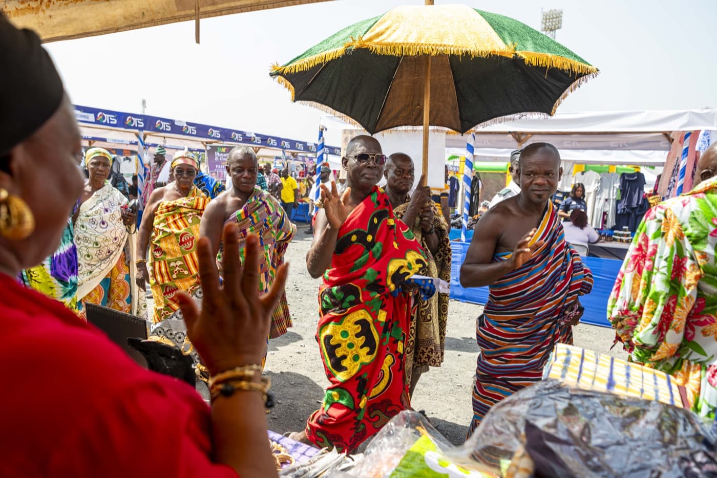 Dignitaries in kente make their way through the exhibition rows