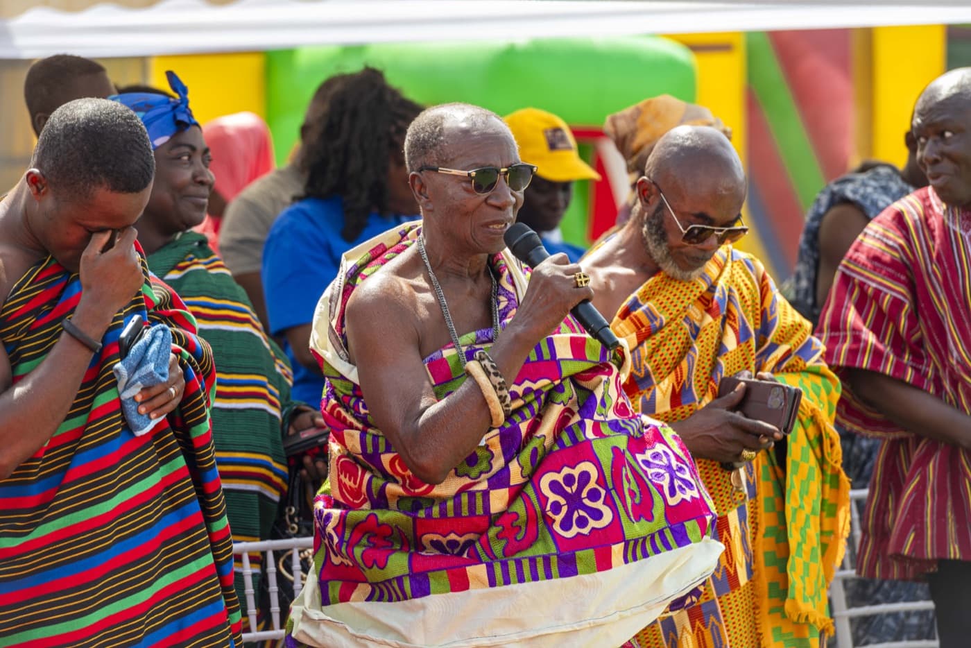 An elder addresses the gathering in colourful smocks